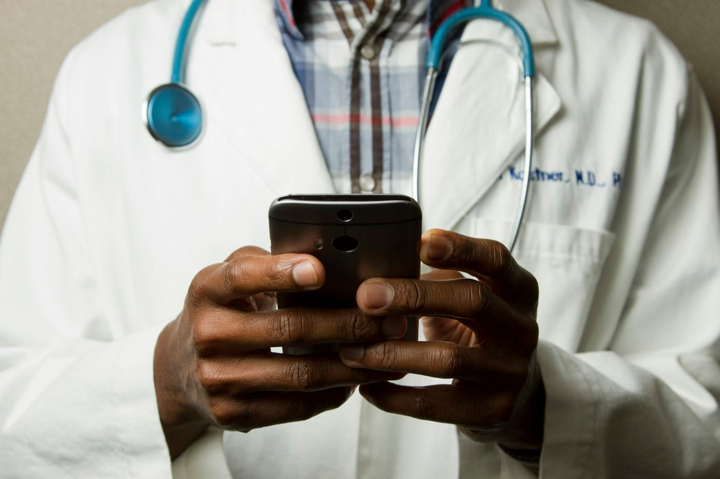 Klinik önlüğündeki bir uzmanın telefonla dijital kayda bakması